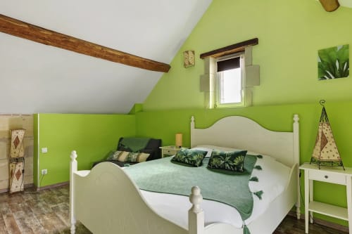 Chambre mansardée vert vif avec lit blanc, poutres apparentes au gîte Le pressoir Le Petit Villeneuve