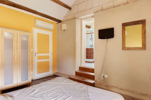 Chambre spacieuse du gîte Le Pressoir au Petit Villeneuve avec lit, portes jaunes, TV et accès salle de bain attenante