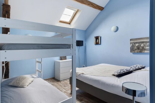 Chambre lumineuse bleu vif avec lits superposés, puits de lumière et mobilier blanc au gîte Le Petit Villeneuve à Saint-Georges-sur-Cher