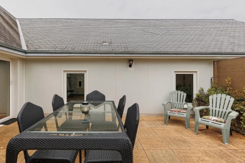 Patio privé avec table à manger, chaises noires et mobilier Adirondack blanc au gîte Le Petit Villeneuve