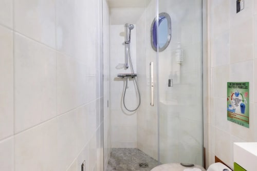 Douche à l'italienne moderne avec paroi vitrée, pommeau de douche cascade et carrelage blanc au gîte Le Petit Villeneuve en France