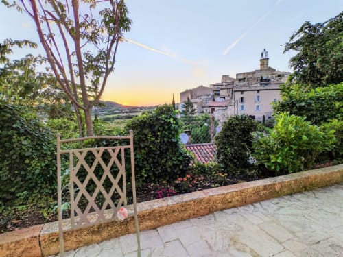 Blick auf den Sonnenuntergang im Dorf Gagnières von der Terrasse des Gartens mit Gittertür, Blumen und üppigem Grün in Mes Maisons