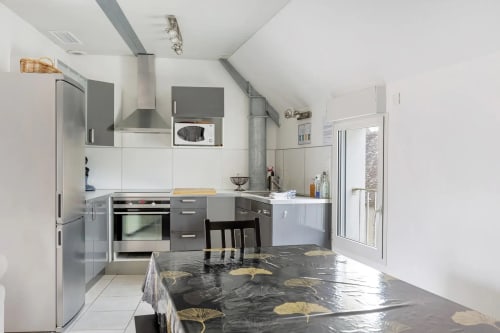 Cuisine moderne du gîte Le Petit Villeneuve avec armoires gris et blanc, électroménagers inoxydables et motifs