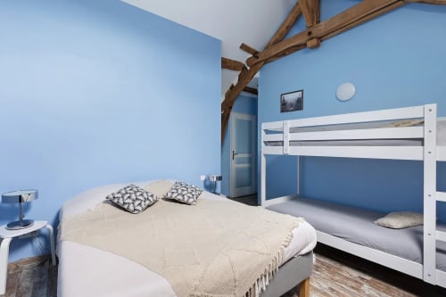 Chambre bleu vif avec lits superposés blancs et lit queen au gîte Le Petit Villeneuve, Saint-Georges-sur-Cher