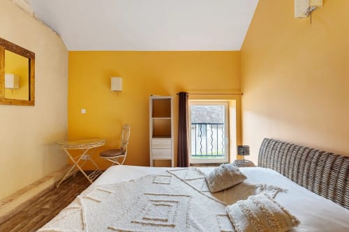 Chambre jaune éclatante au gîte Le Petit Villeneuve avec lit, vue sur le jardin, bureau de travail et équipements modernes