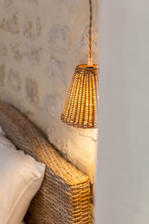 Glowing woven pendant lamp hanging against textured wall at Mas Bella Cortis, La Garde-Adhémar