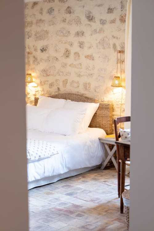 Cozy bedroom at Mas Bella Cortis B&B in La Garde-Adhémar with rustic stone walls, white bedding, and warm pendant lighting