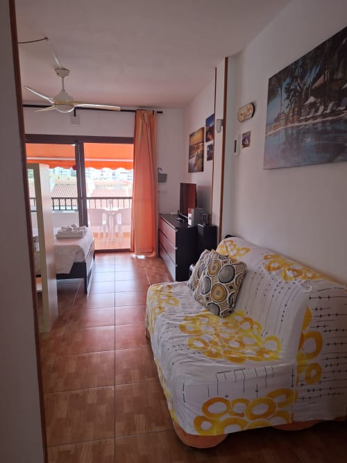 Bedroom with yellow patterned bedding in Costa Adeje apartment, view to balcony and pool area