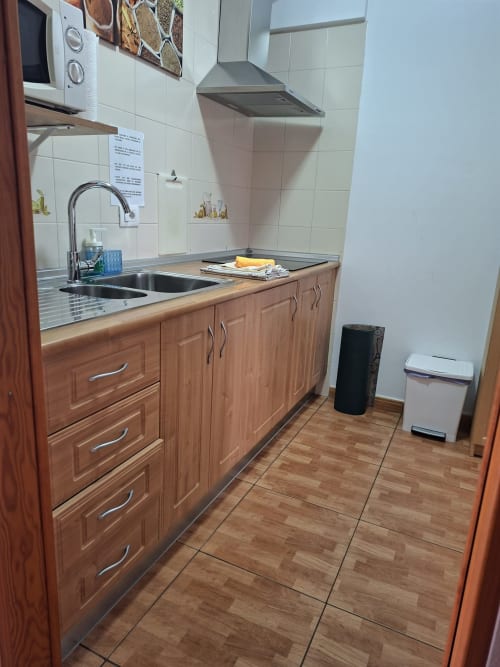 Modern kitchen with wooden cabinets, stainless steel sink, cooker, and range hood in Costa Adeje apartment