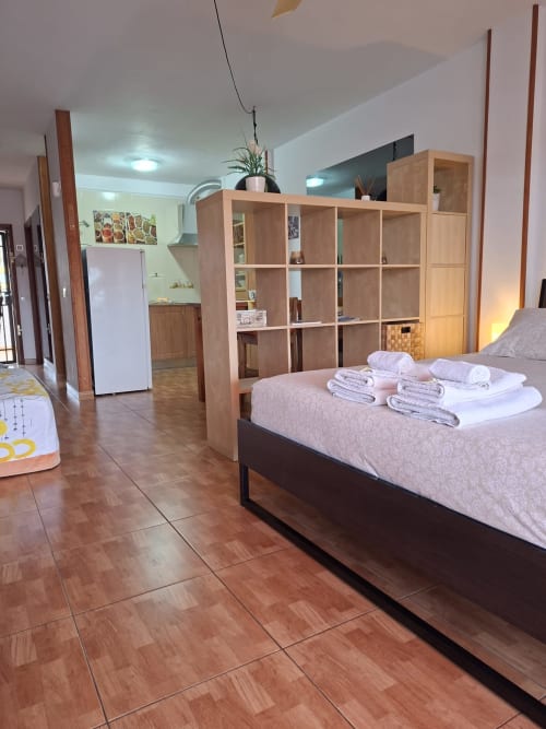 Studio apartment in Costa Adeje, Tenerife with bed, wooden shelving unit, kitchenette, and tiled flooring