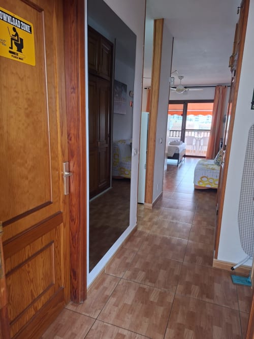 Hallway in Costa Adeje apartment with wooden doors, tiled flooring, and view to balcony with pool view