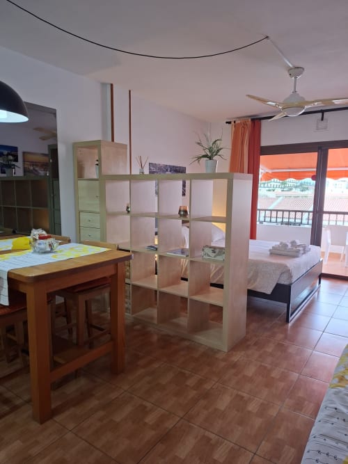 Studio apartment in Costa Adeje, Tenerife with open-plan living, wooden shelving divider, dining table, and bedroom with