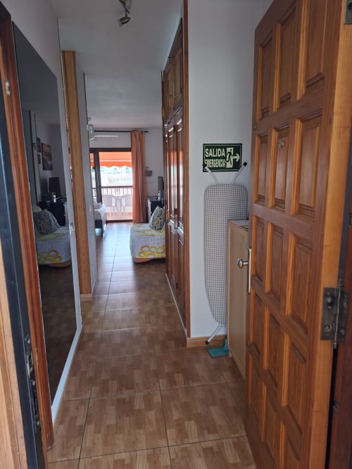 Hallway with wooden doors and tile flooring in Costa Adeje apartment, emergency exit sign visible