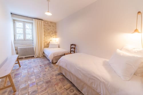 Bright bedroom at Mas Bella Cortis B&B in La Garde-Adhémar with two beds, terracotta floor, and rustic French decor