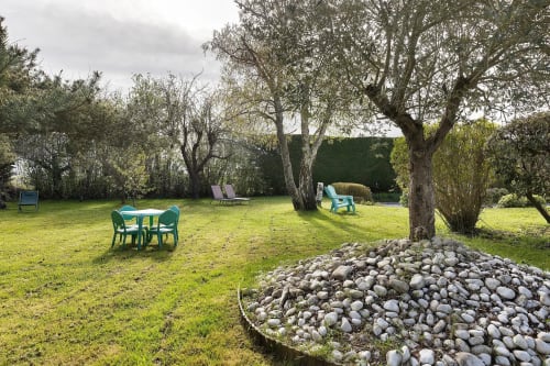 Jardin luxuriant du Gîte Le Petit Villeneuve avec espaces de détente verdoyants, arbres matures et éléments en pierre à Saint-Georges-sur-Cher