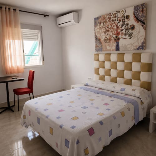 Habitación doble en Hostal Europa de Aldaia con cama de ropa de cama estampada, cabecero cuadriculado, escritorio y aire acondicionado