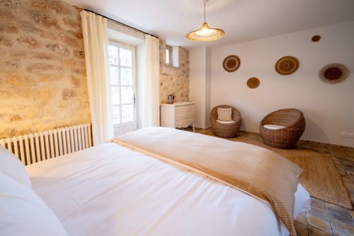 Rustic bedroom at Mas Bella Cortis B&B in La Garde-Adhémar with stone walls, woven chairs, and warm lighting