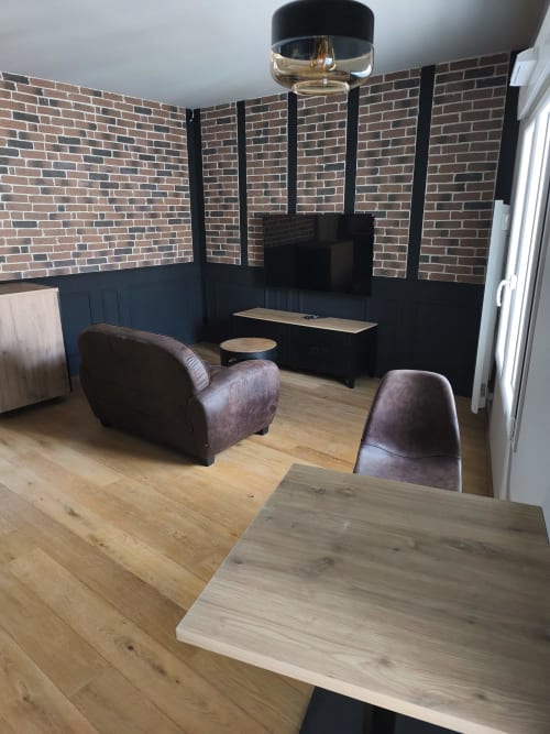 Salon loft moderne à Escale à Clisson avec murs en briques apparentes, fauteuil en cuir et table de salle à manger en bois