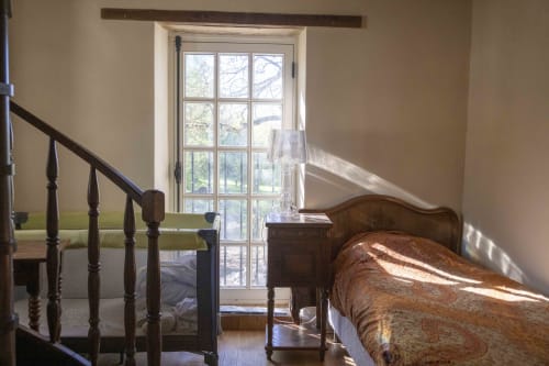 Chambre lumineuse avec lit en bois et escalier, vue sur le jardin par les grandes portes-fenêtres à la Cour Du Liège
