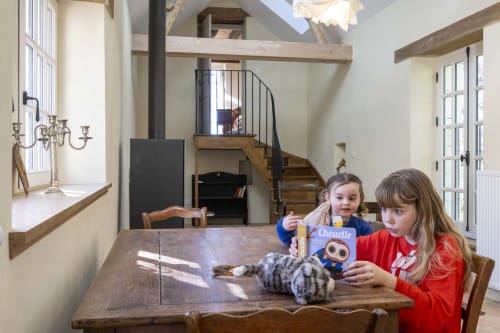 Deux enfants s'amusent à la table à manger en bois du gîte Le Colombier à Cour Du Liège, Baugé-en-Anjou, avec mezzanine