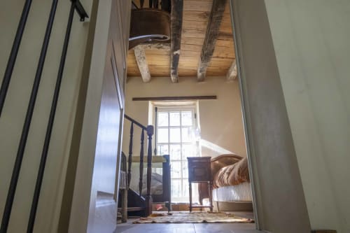 Chambre de la chaumière Le Colombier à la Cour Du Liège avec poutres apparentes, garde-corps métallique et vue sur le jardin