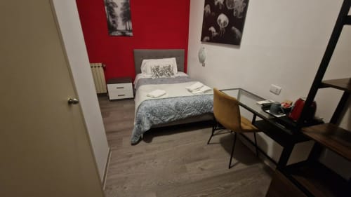 Single bedroom at Hotel Genzianella, Florence with red accent wall, twin bed, desk, and wooden flooring