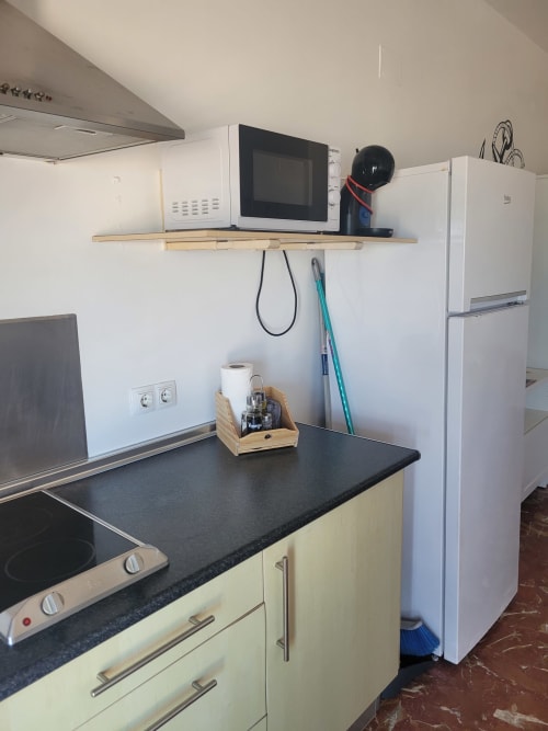 Cocina moderna con microondas, estufa, refrigerador y encimera negra en estudio con vistas al mar del hotel Matalascañas