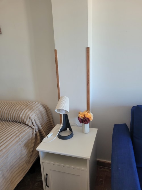 Mesita de noche con lámpara de escritorio y flores en apartamento de Matalascañas con vistas al mar