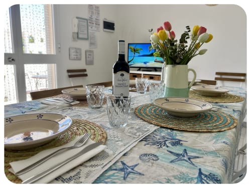 Elegant dining table setup at Villa Adua in Ostuni with place settings, wine bottle, colorful tulips, and sea-themed
