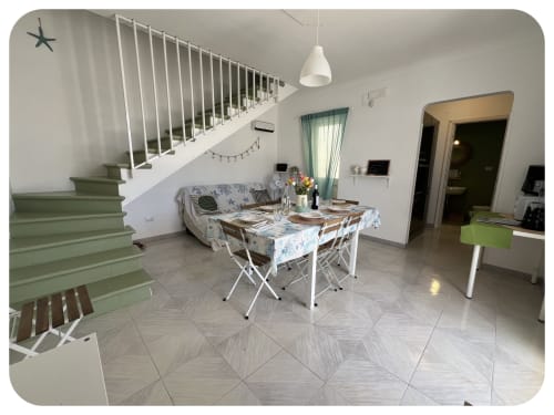 Modern villa dining area with green staircase, set table, and living space at Dimore Adua, Ostuni