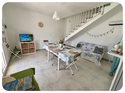 Villa Adua living area with dining table, sofa, TV, and staircase in Ostuni villa