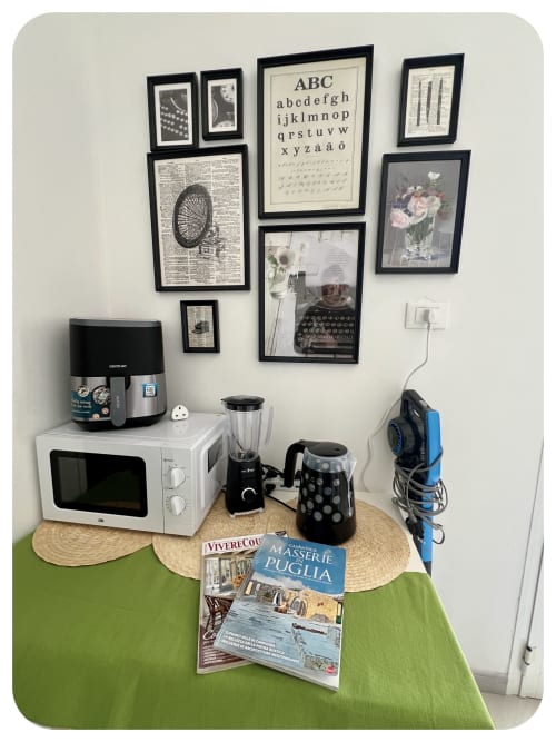 Kitchen corner in Villa Adua, Ostuni with microwave, air fryer, blender, and wall art above green table