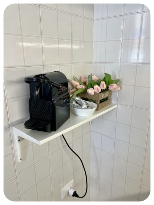 White kitchen shelf with black coffee machine, pink tulips in wooden planter, and white bowl at Villa Adua in Ostuni