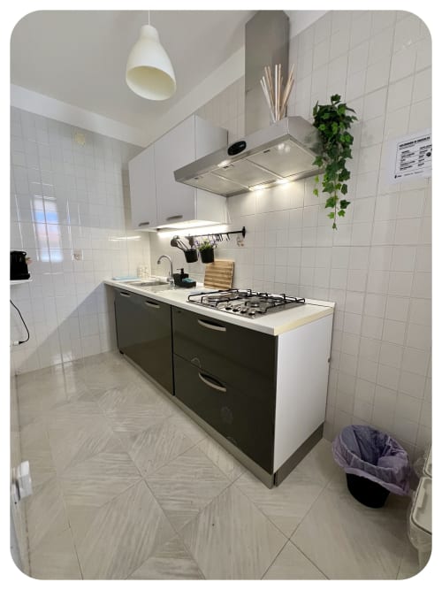 Modern kitchen in Villa Adua with gas cooktop, stainless steel hood, white tiles, and dark cabinetry at Dimore Adua, Ostuni