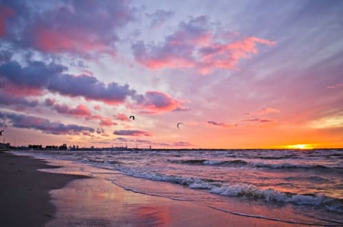 Tramonto sulla spiaggia di Ostuni con onde, cielo colorato e kitesurfisti presso Dimore Adua
