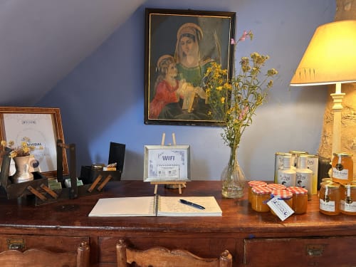 Rustic desk at Casa Gallinera with religious artwork, flowers, WiFi sign, and local products in Alicante