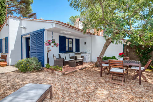 Cour de Finques Garcia Enrich à Palafrugell : villa blanche, volets bleus, mobilier de jardin et zone ombragée