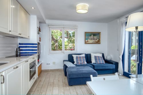 Cuisine ouverte et séjour contemporain avec canapé bleu, mobilier blanc et balcon à Finques Garcia Enrich à Palafrugell