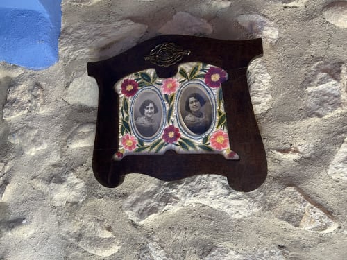 Vintage floral frame with twin portraits mounted on rustic stone wall at Casa Gallinera, Alicante