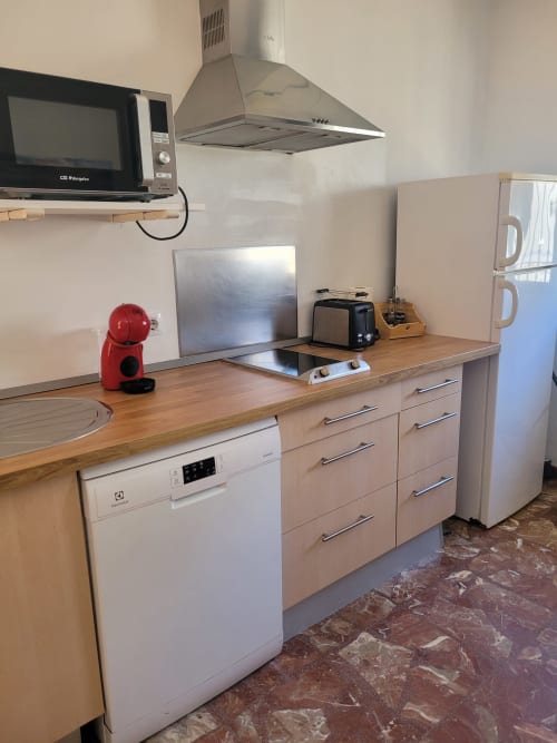 Cocina moderna en apartamento de Matalascañas con encimeras de madera, electrodomésticos y campana extractora de acero inoxidable