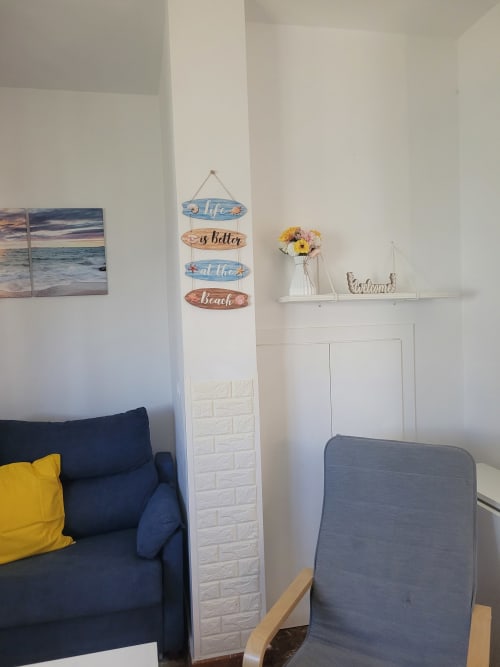 Sala de estar de apartamento costero con decoración temática marina, sofá azul marino y cuadros con vistas al mar en Apartamentos A la Orilla del Mar