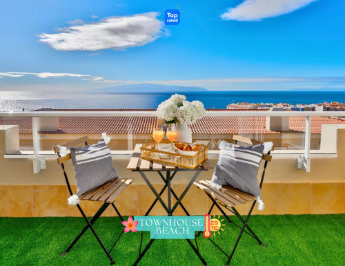 Terraza de lujo frente al mar en Adeje con vistas al océano, tumbonas y pueblo costero