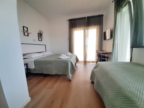 Camera moderna del B&B Bari Centro con due letti, pavimenti in legno e porte con vista sul giardino a Bari, Italia