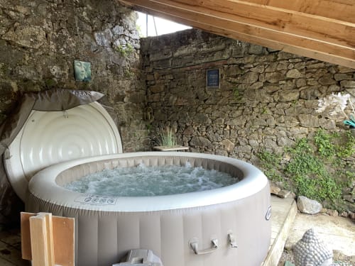 Jacuzzi gonflable avec jets d'eau dans un abri aux murs en pierre au Petit Moulin, Pouzauges