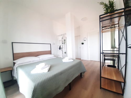 Camera moderna del B&B Bari Centro con letto in legno, biancheria grigia, pavimenti in legno e pareti bianche a Bari, Italia