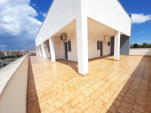 Ampia terrazza panoramica del B&B Bari Centro con pavimento in cotto, colonne bianche e vista sulla città di Bari, Italia