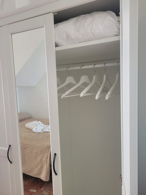 Armario abierto en Apartamento 6 con perchas de madera blanca y ropa de cama en Apartamentos A la Orilla del Mar, Matalascañas