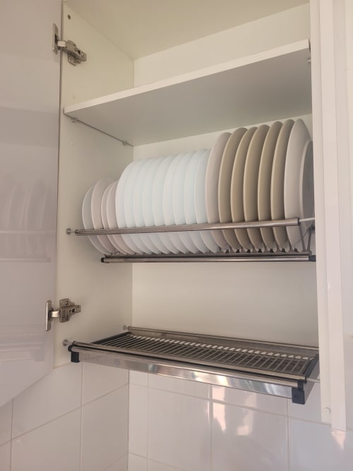 Armario de cocina con escurreplatos blanco y secador de platos de acero inoxidable en apartamento de Matalascañas