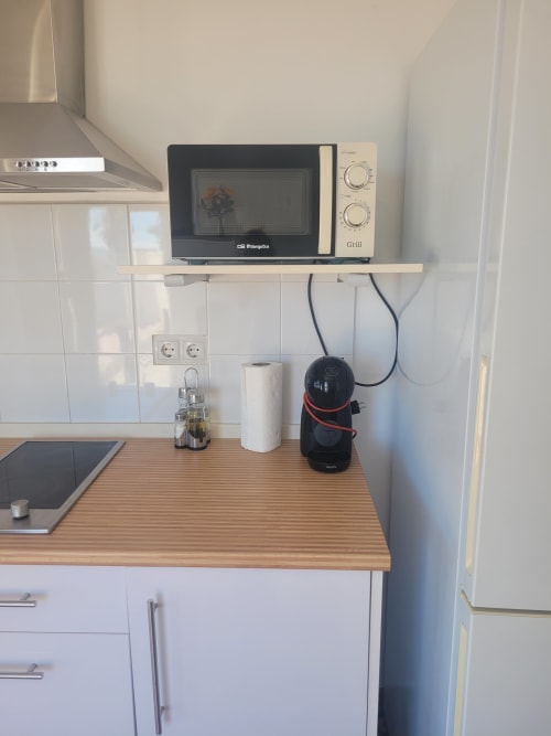 Cocina moderna en apartamento de Matalascañas con microondas, encimera de madera y muebles blancos