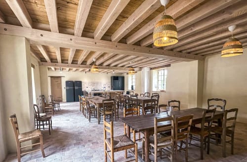 Salle à manger rustique à la Cour Du Liège avec plafond à poutres apparentes, tables multiples avec chaises paillées et luminaires tressés